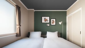A hotel room with two beds, a green accent wall, and artwork. - SUN FRIENDS 201 (Asahikawa)
