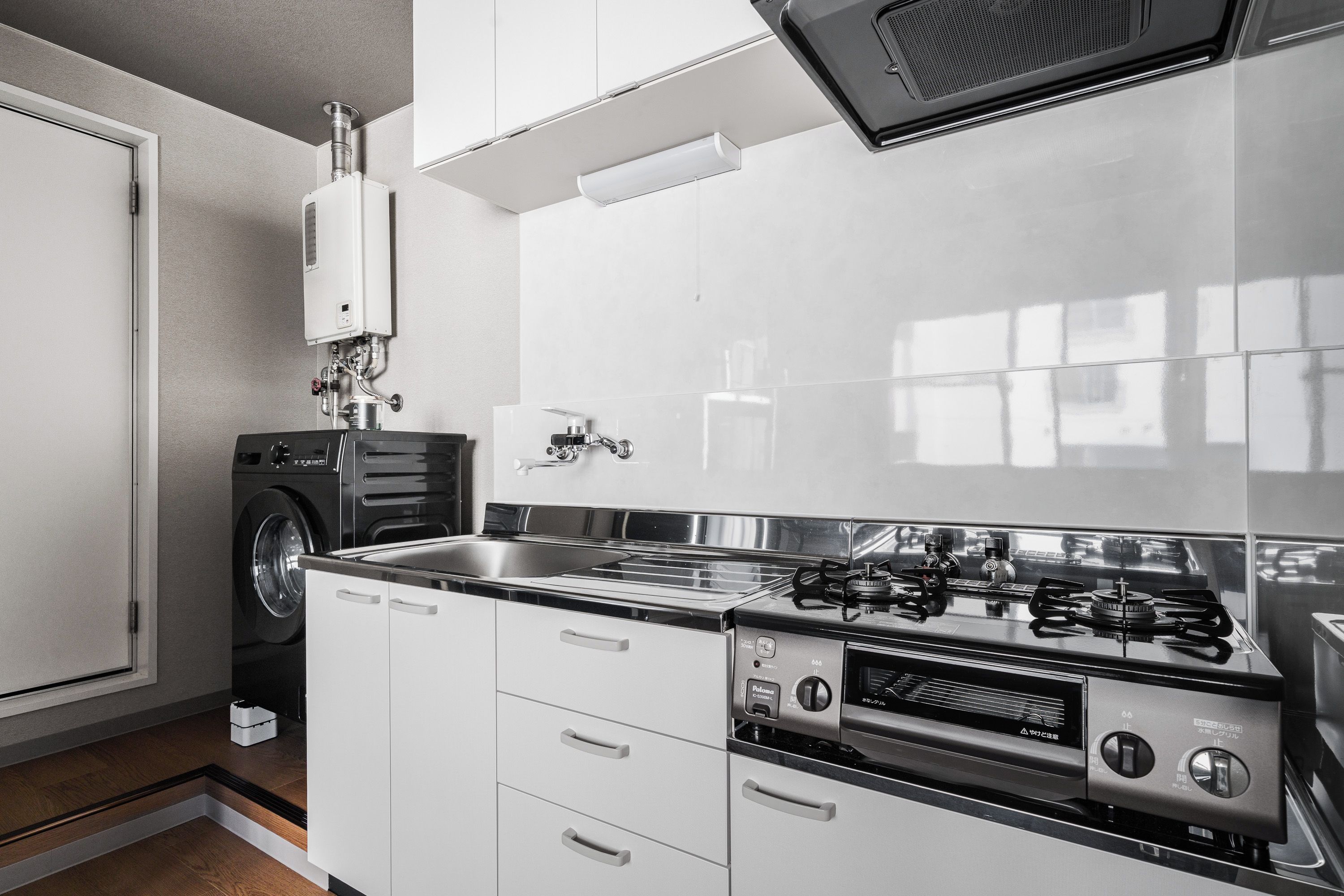 A modern kitchen with a built-in washer, a stainless steel sink, and a gas stove.