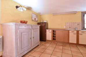Eine Küche mit weißen Schränken, einem Kühlschrank und einer gefliesten Spritzschutzwand.