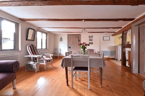 A dining area with a table set for four, wooden floors, and a ceiling with exposed beams. - Holiday apartment with 1 bedroom (Jebsheim)