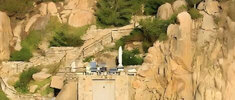 Un bâtiment situé sur la côte, doté d’une façade en pierre, d’un escalier menant à un quai et d’une statue au premier plan.