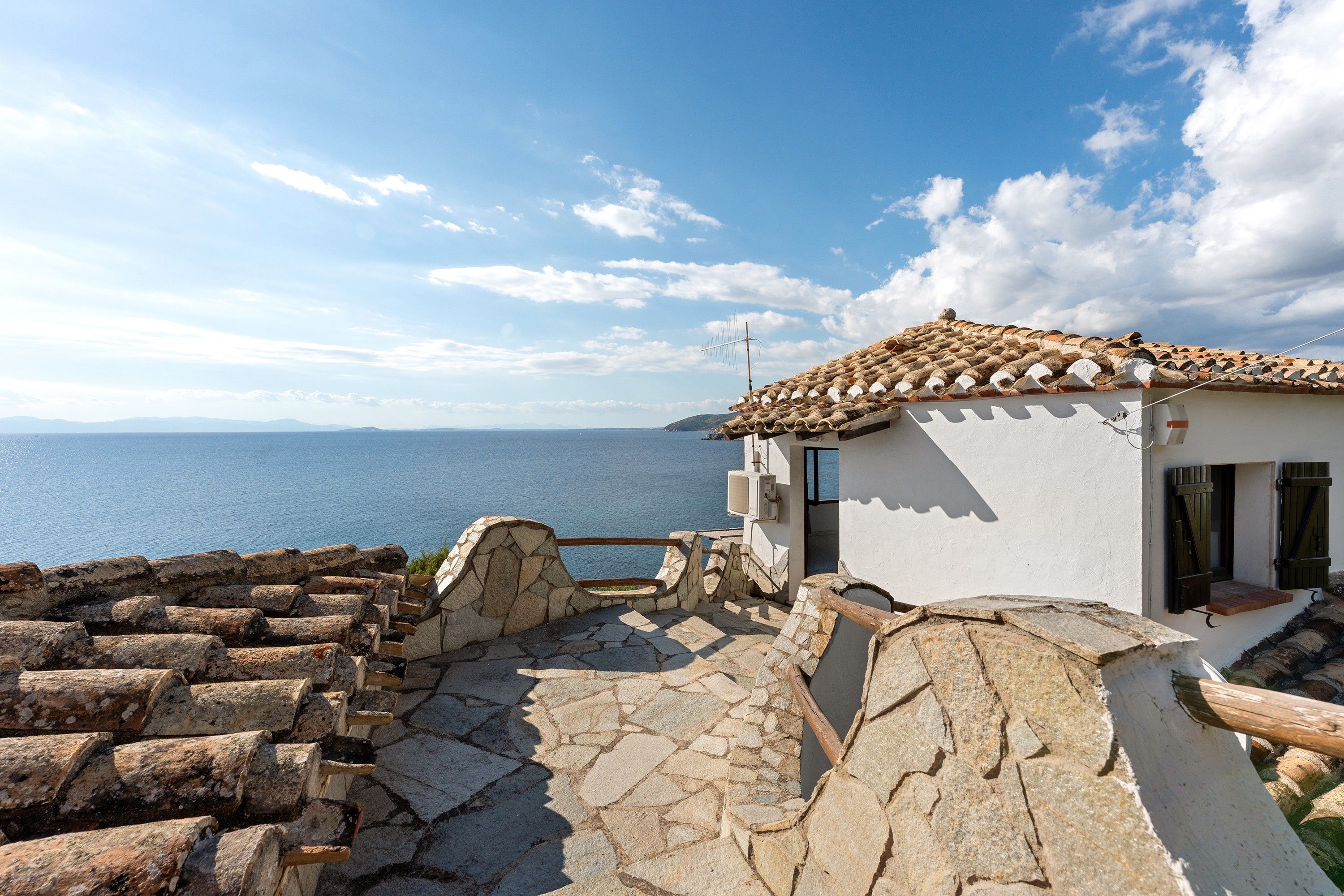 Un edificio costero con una escalera de piedra que lleva a una terraza con vistas al mar.