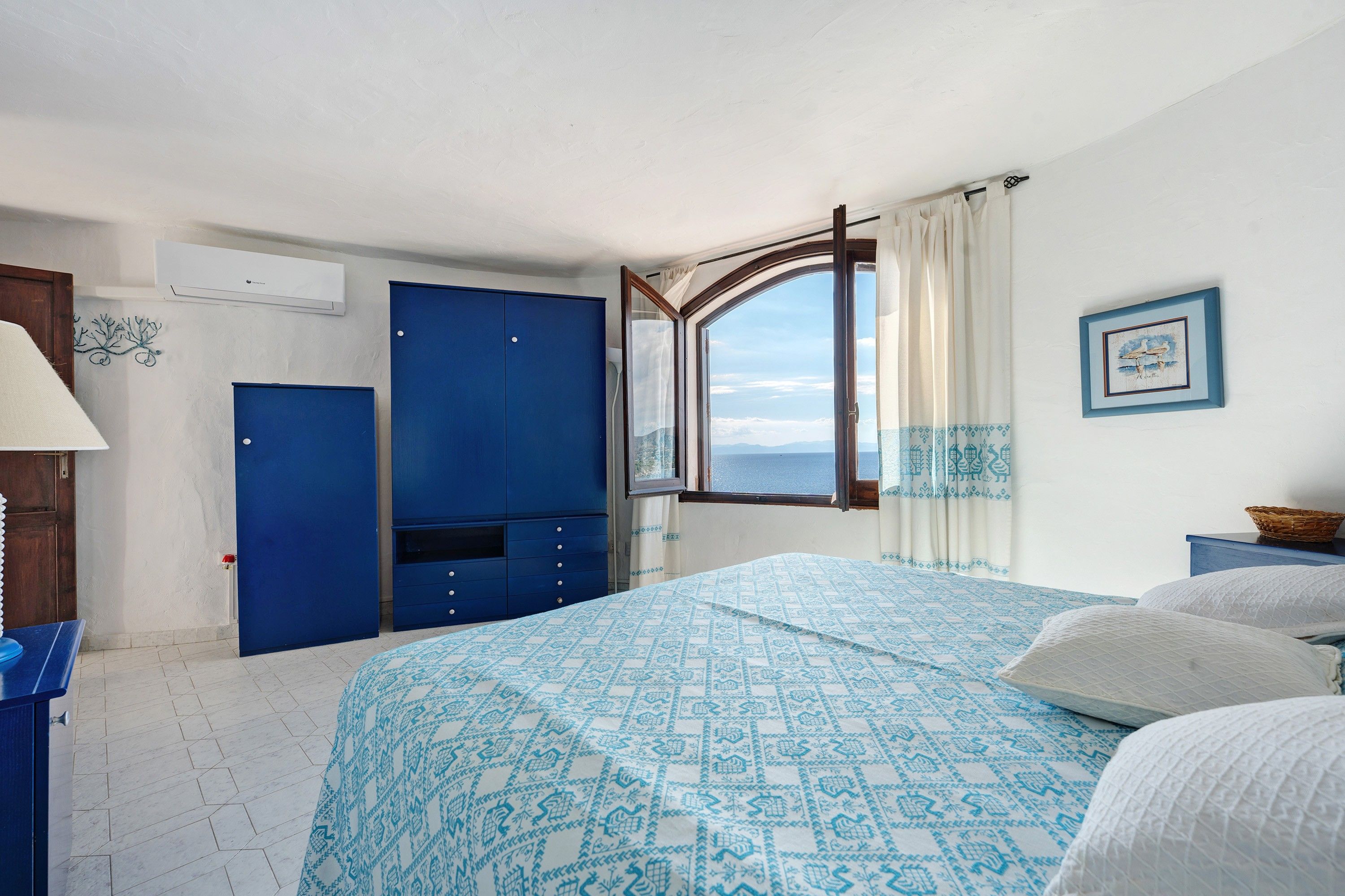 A room with a bed, a wardrobe, a window with a view, and a wall-mounted air conditioner.