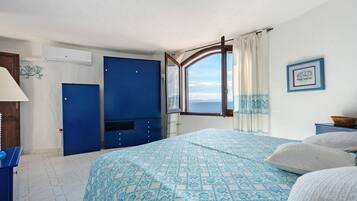 A room with a bed, a wardrobe, a window with a view, and a wall-mounted air conditioner.