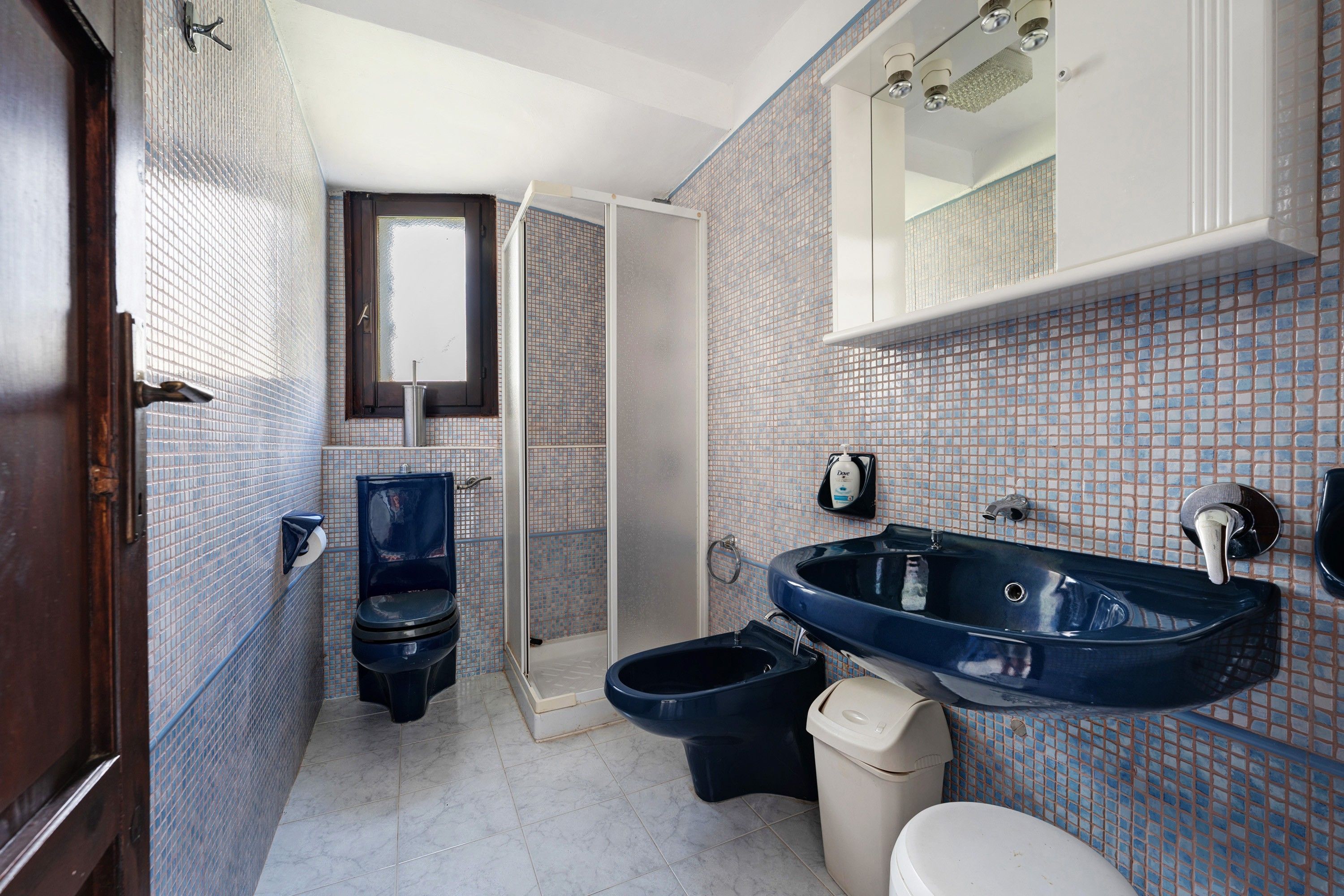 Une salle de bain comprenant des toilettes, un bidet, un lavabo et un miroir au-dessus du lavabo.