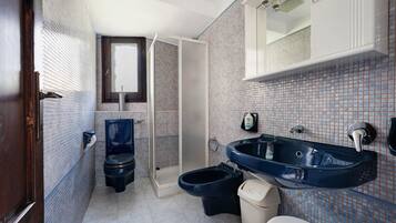 Une salle de bain comprenant des toilettes, un bidet, un lavabo et un miroir au-dessus du lavabo.