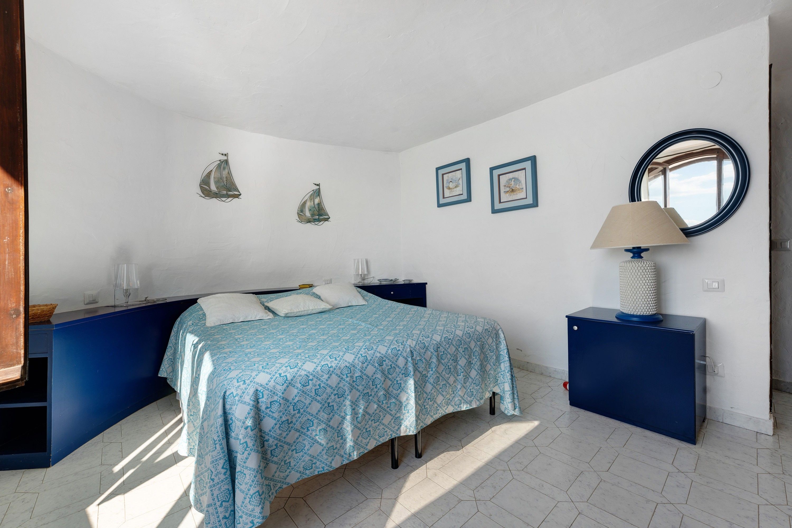 A bedroom with a bed, a nightstand, a dresser, a lamp, and wall decorations.