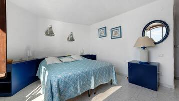 A bedroom with a bed, a nightstand, a dresser, a lamp, and wall decorations.