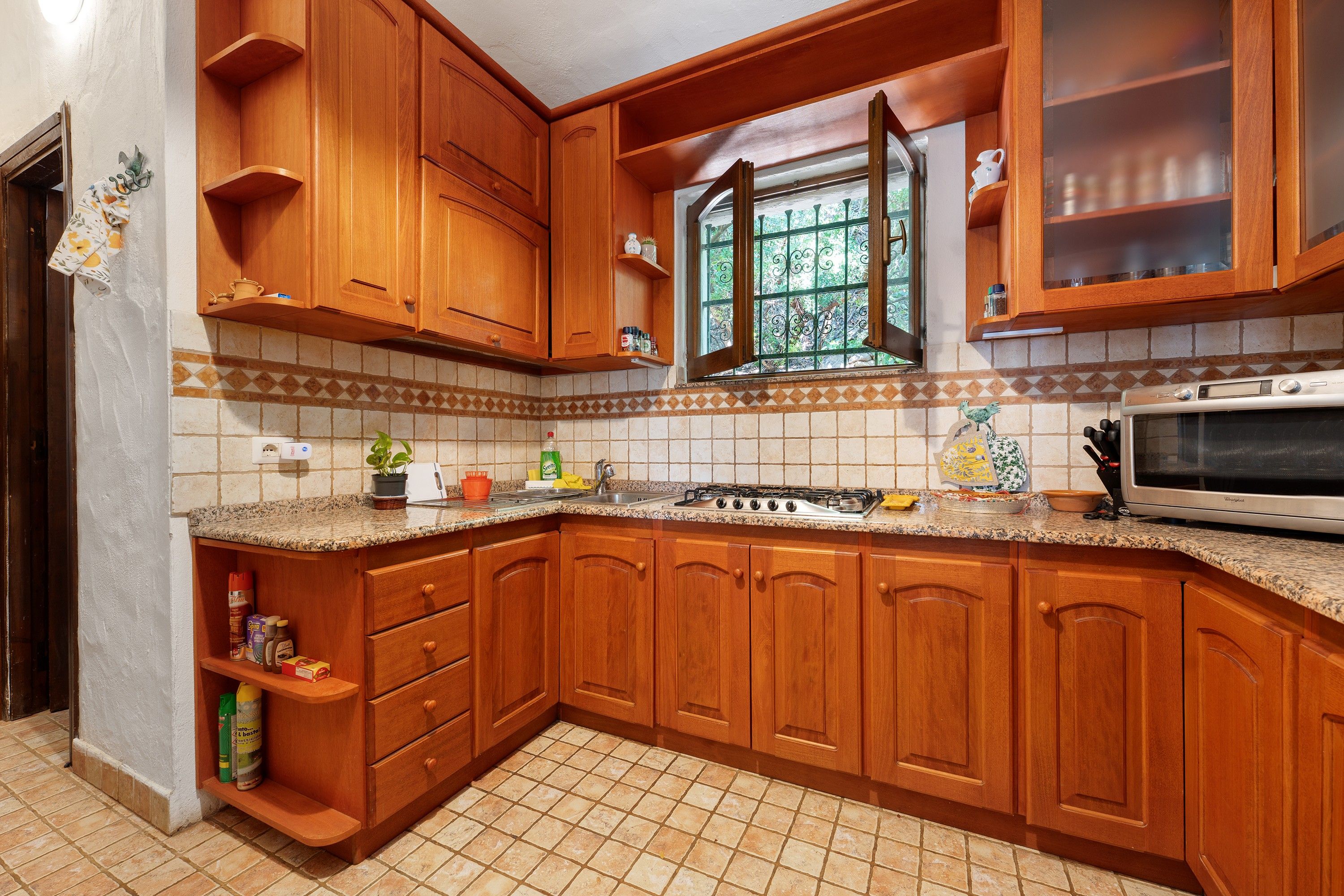 Una cucina con mobili in legno, un fornello a gas e un forno a microonde.