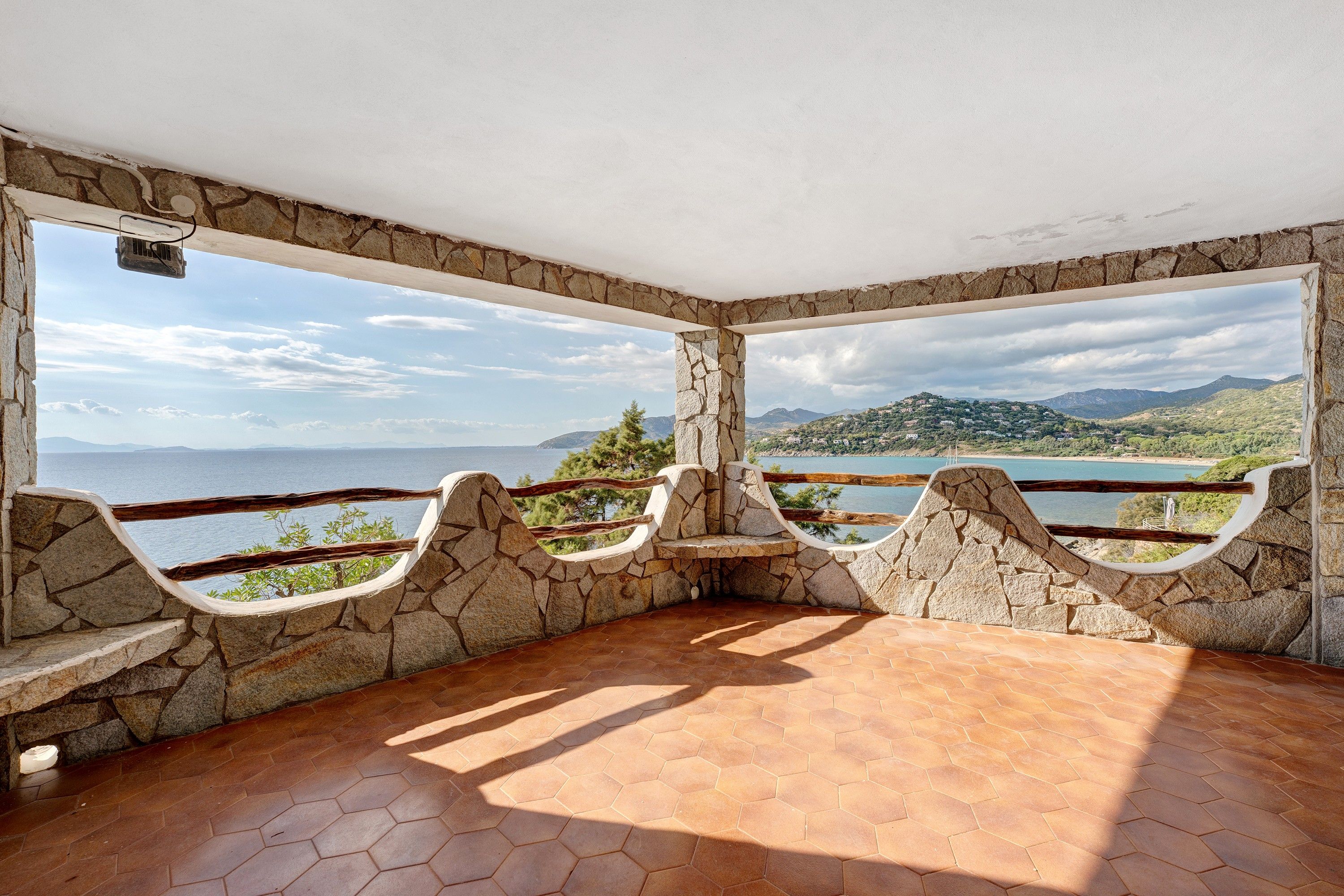 A stone-walled room with a view of a lake and mountains.