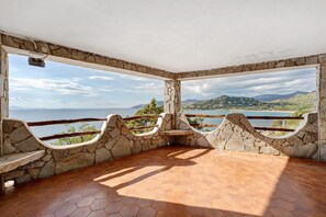 A stone-walled room with a view of a lake and mountains.