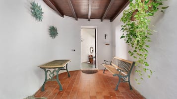 Une pièce avec un banc en bois, une table et une plante suspendue.