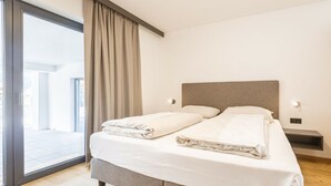Un dormitorio moderno con una cama grande, un ventanal corredero y vistas al exterior.