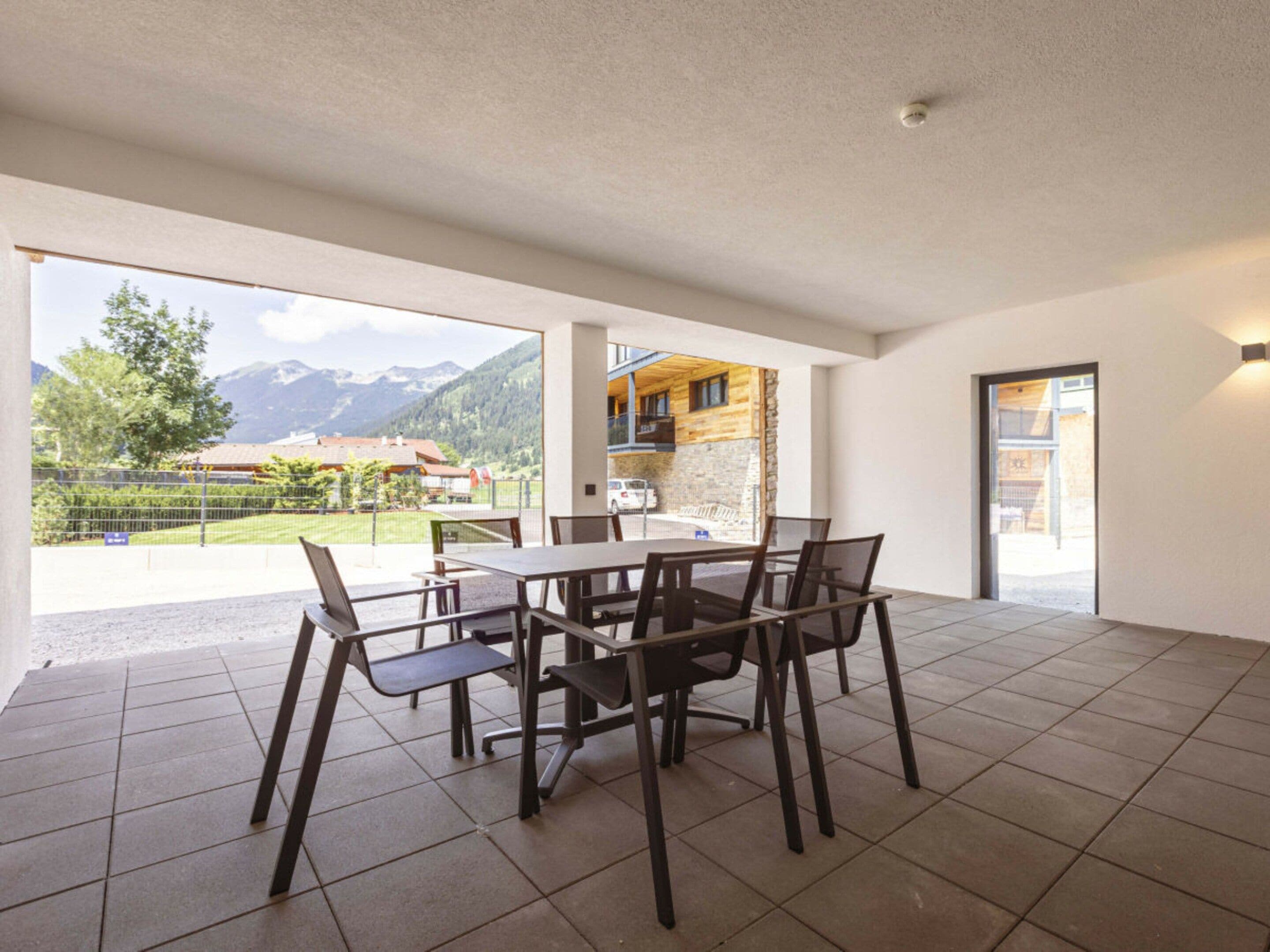 A spacious room with a dining table and chairs, a view of mountains, and a door leading to an outdoor area.