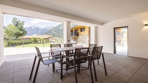 Amplia habitación con una mesa de comedor y sillas, vista a montañas y puerta que da a un espacio exterior.