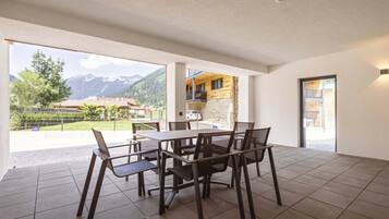 A spacious room with a dining table and chairs, a view of mountains, and a door leading to an outdoor area.