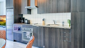 Een moderne keuken met donkere houten kastjes, roestvrijstalen apparatuur en een betegelde spatwand.