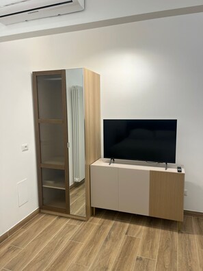 Ein Zimmer mit integriertem Fernseher, einem Schrank mit Spiegel und einem Heizkörper.