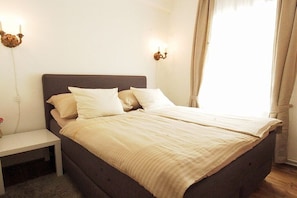 A bedroom with a bed, bedside tables, and wall-mounted lamps.