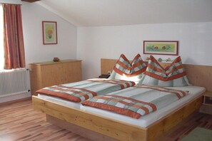 Ein Schlafzimmer mit einem hölzernen Bett, einem Nachttisch, einer Kommode und zwei an der Wand befestigten Bildern.