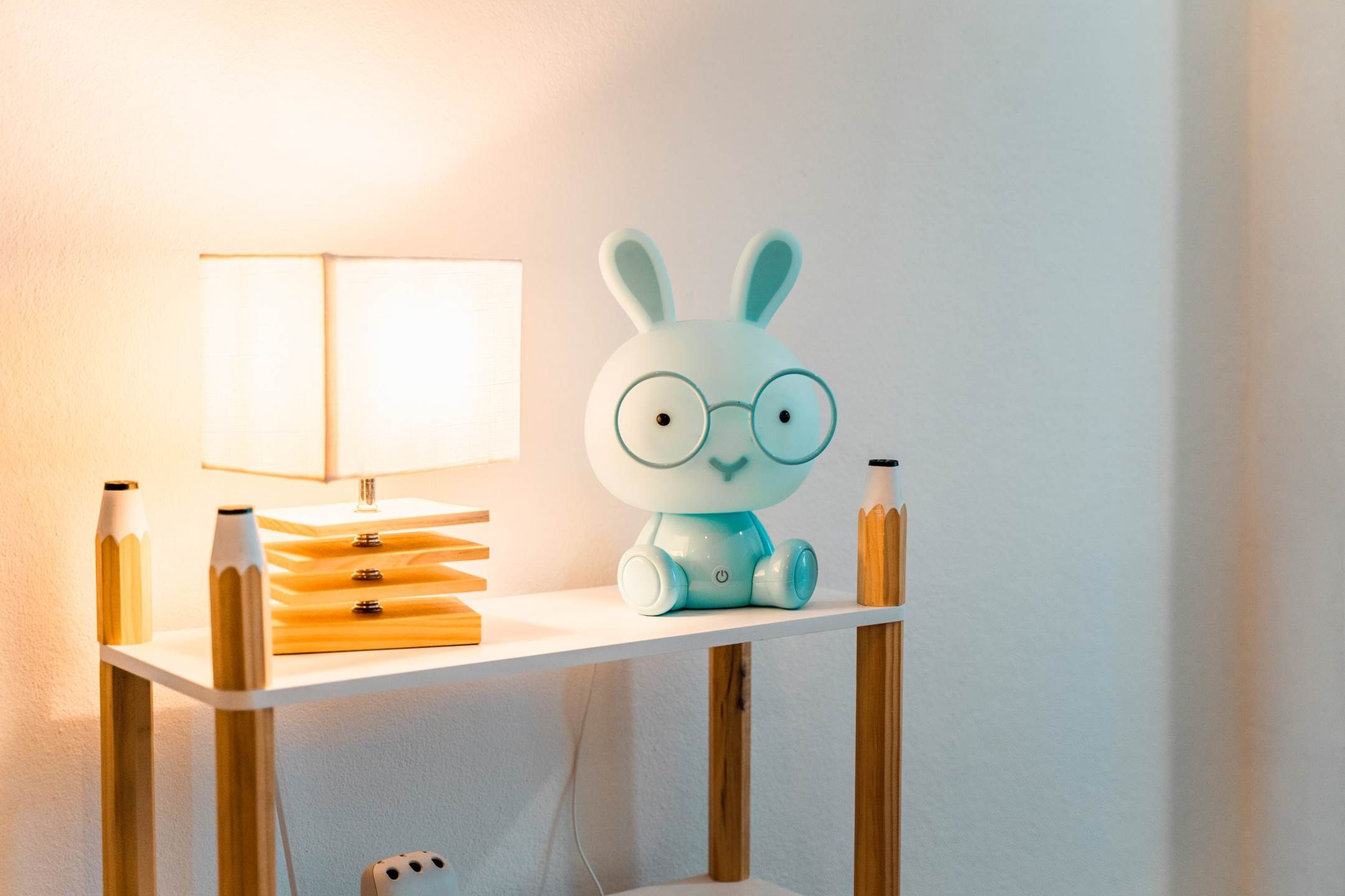 A table with a lamp, a stack of books, and a decorative rabbit figurine.
