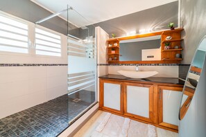 Un bagno moderno con cabina doccia in vetro, un mobile bagno in legno con lavandino e uno specchio sopra il mobile.