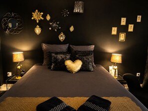 Una camera da letto con un letto grande, due lampade ai comodini, decorazioni murali e un cuscino a forma di cuore.