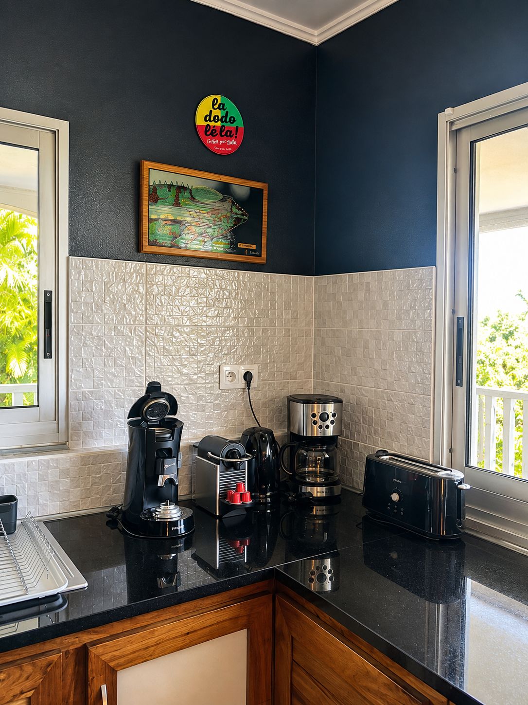 Une cuisine équipée d’une machine à café, d’un grille-pain et ornée d’un tableau au mur.