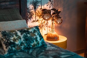 Ein Bett mit einem gemusterten Kissen und einer dekorativen Lampe mit einer strukturierten Schirm auf einem Nachttisch aus Holz.