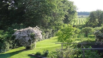 A garden with a variety of trees and shrubs, a well-maintained lawn, and a wooden fence.
