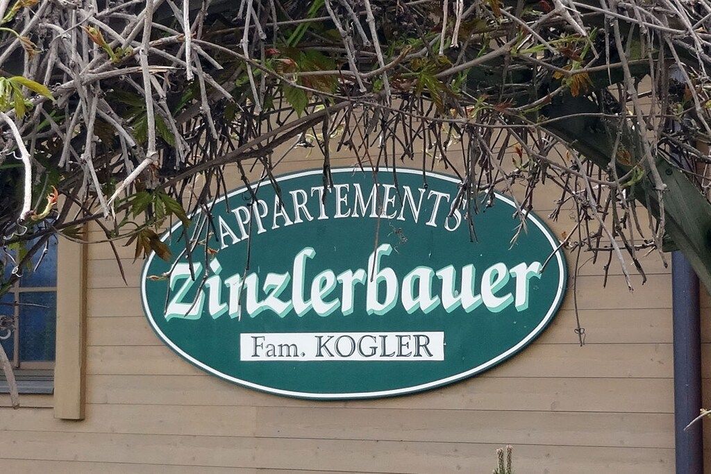 Une enseigne indiquant « Zinzlerbauer Apartments », avec une plaque portant le nom « Fam. Kogler ».