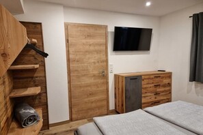 Une chambre à coucher avec un lit, une armoire en bois, un téléviseur et une porte.