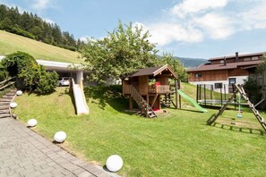 Ein Wohngebiet mit einem Spielhäuschen, einer Rutsche und einem umzäunten Spielplatz.