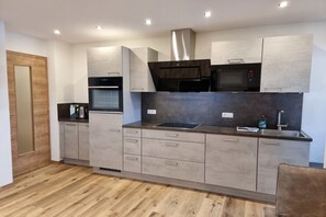 Eine moderne Küche mit integrierten Geräten, grauen Schränken und Holzboden.