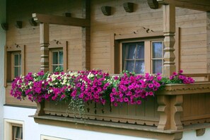 Ein hölzernes Gebäude mit einem Balkon, der eine Blumenkiste mit rosa und weißen Blumen zeigt.