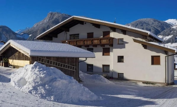 A chalet with a sloped roof, wooden balcony, and a snow-covered ground. - Alpenstern Fewo Tristner (Ramsau)