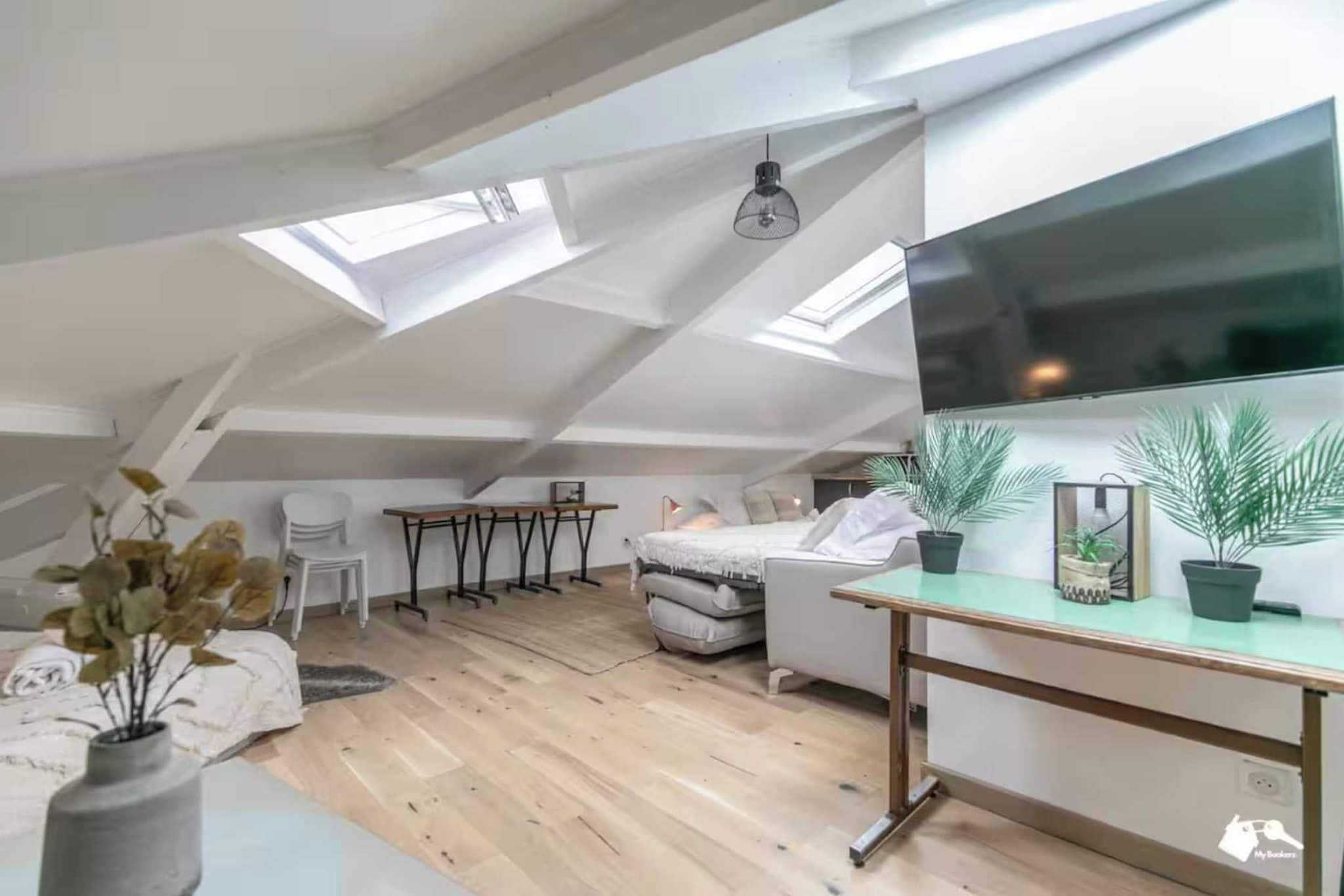 Een kamer in loftstijl met een schuine plafond, een bed, een bureau en een stoel.