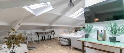 A loft-style room with a sloped ceiling, a bed, a desk, and a chair.