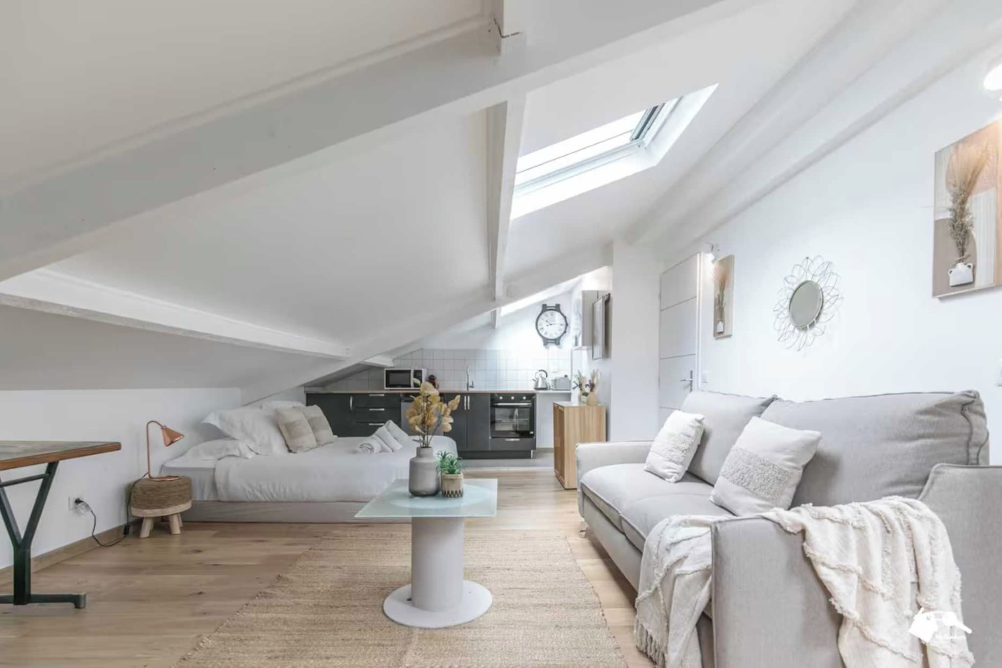 A modern loft apartment with a dining area, a sofa, a coffee table, and a kitchen in the background.