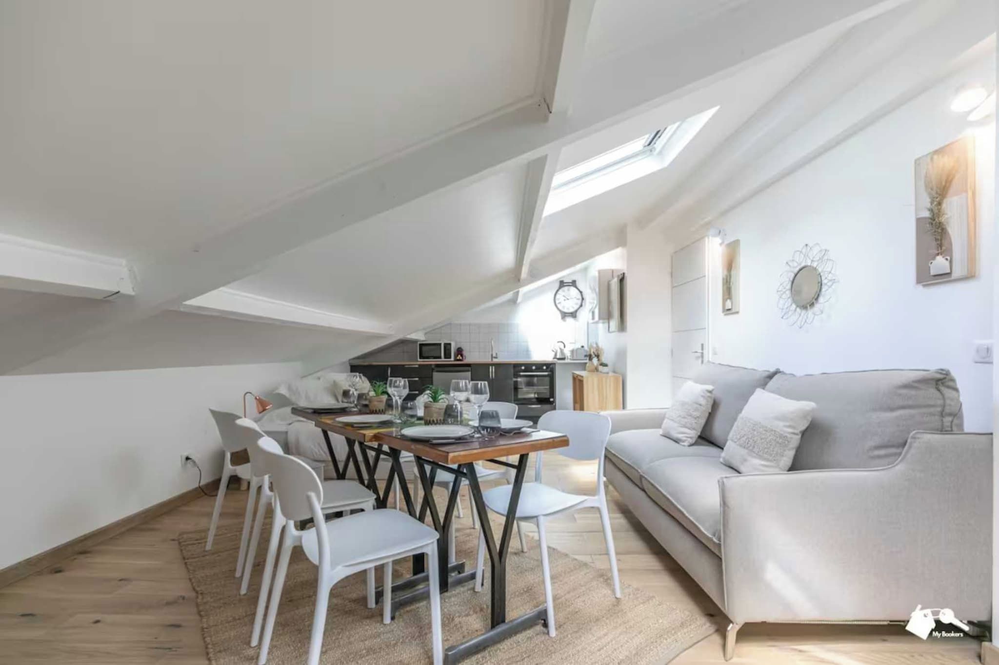 A modern loft apartment with a dining area, kitchenette, and a living space with a sofa and decorative items.