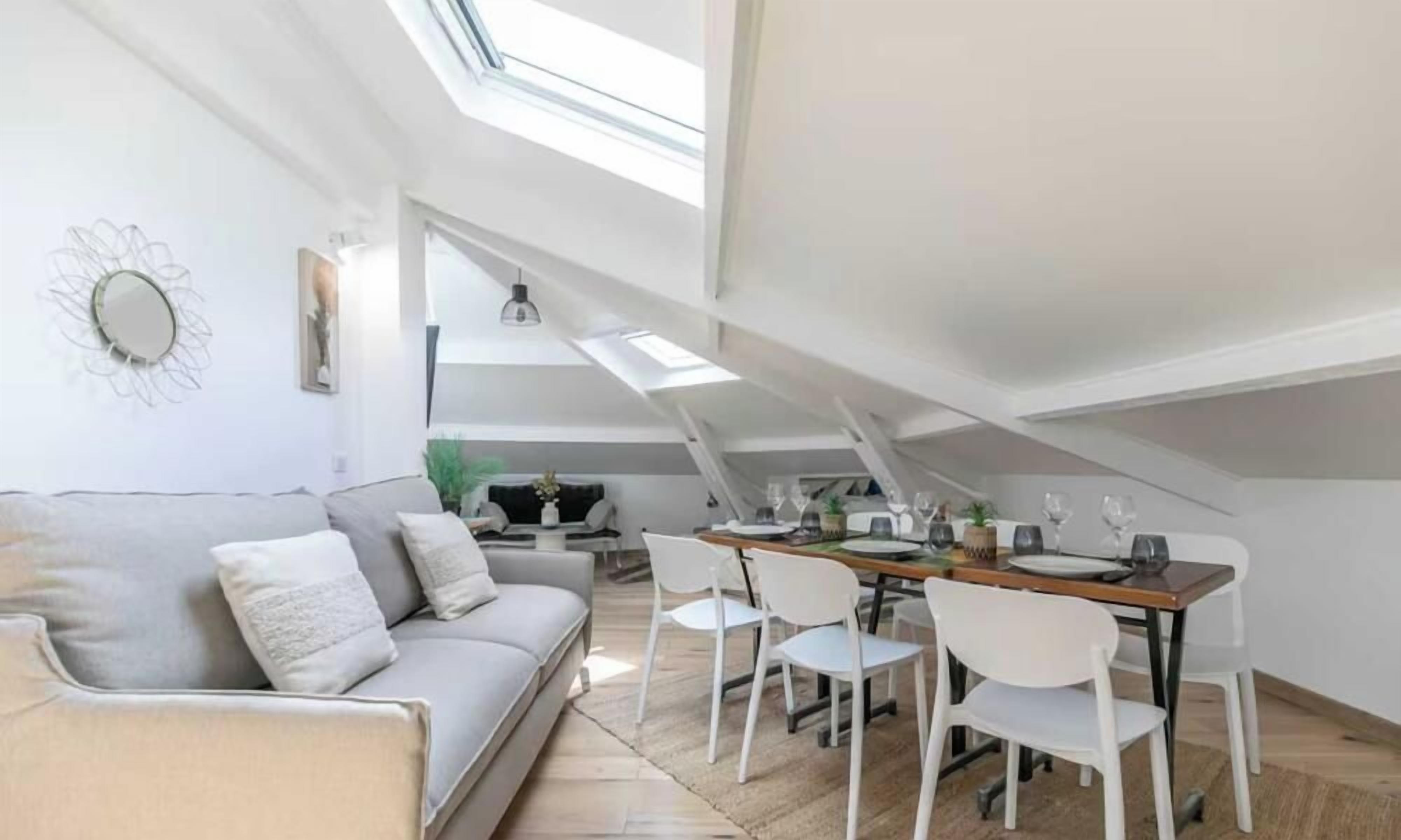 Un espacio habitable tipo loft con zona de comedor, techos altos, tragaluces y una estética moderna.
