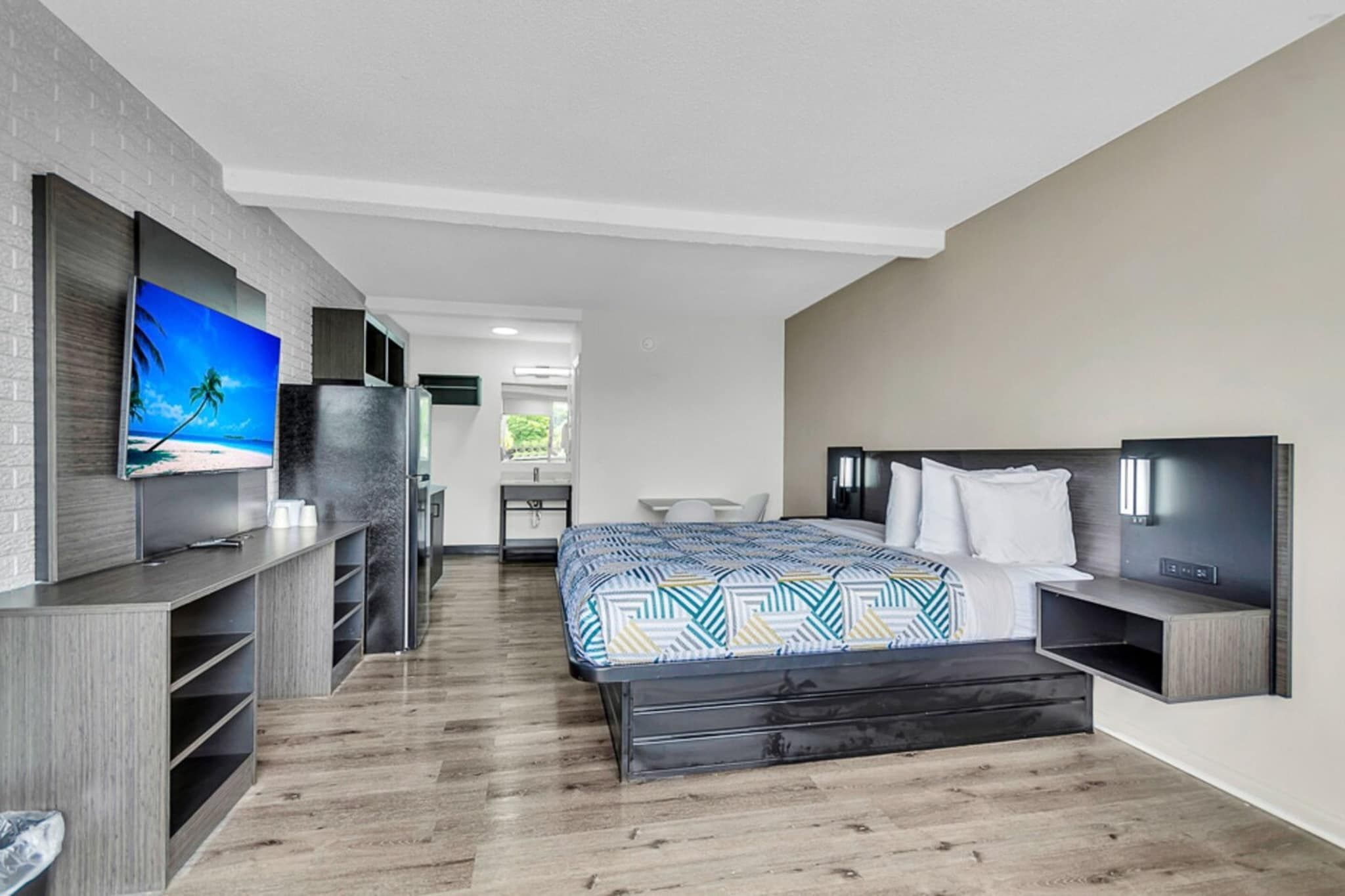 Une chambre d’hôtel moderne équipée d’un lit, d’une télévision, d’un bureau et d’une kitchenette.