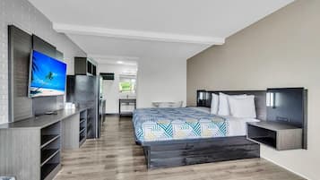 Une chambre d’hôtel moderne équipée d’un lit, d’une télévision, d’un bureau et d’une kitchenette.