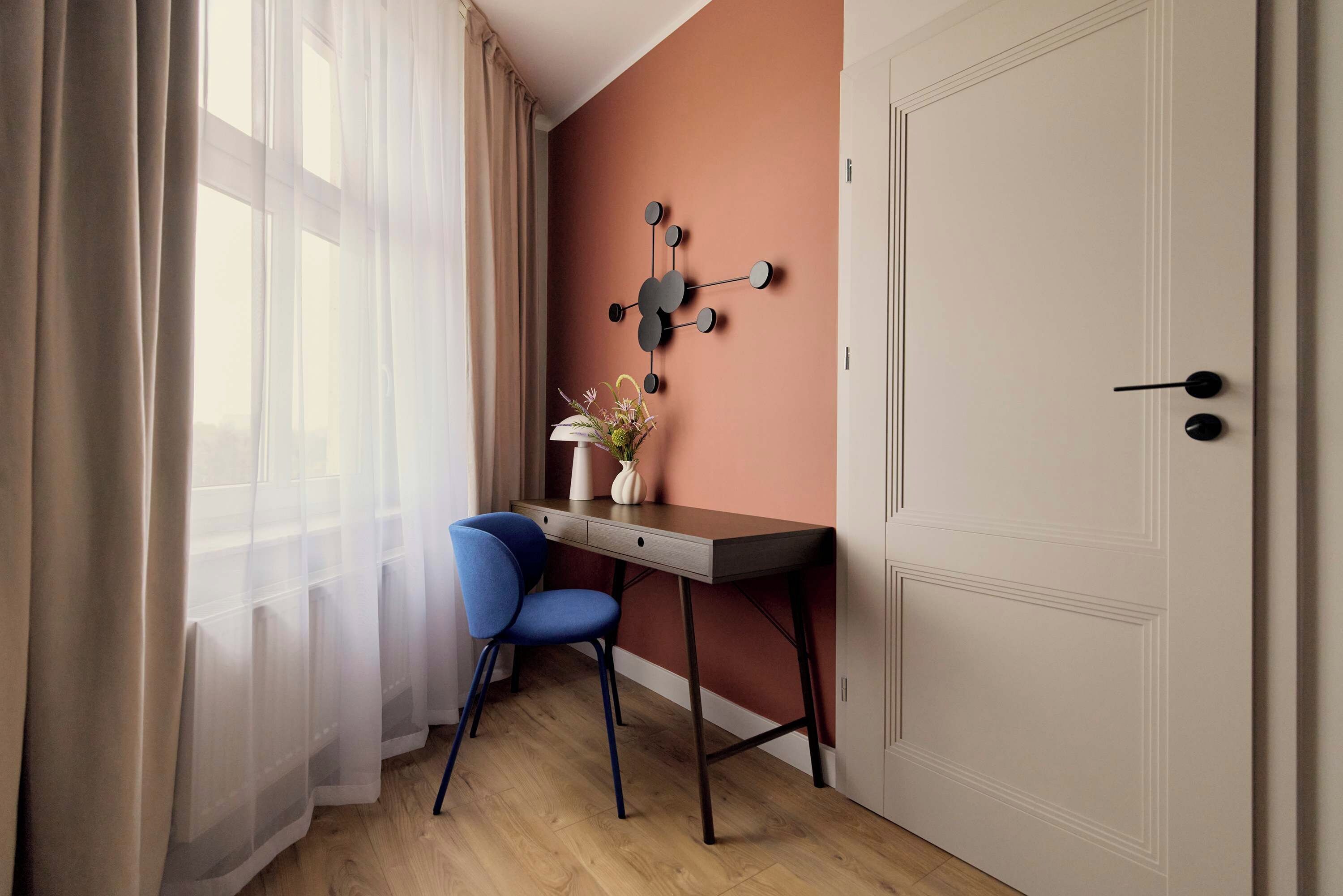 A room with a desk, chair, and a wall-mounted light fixture.