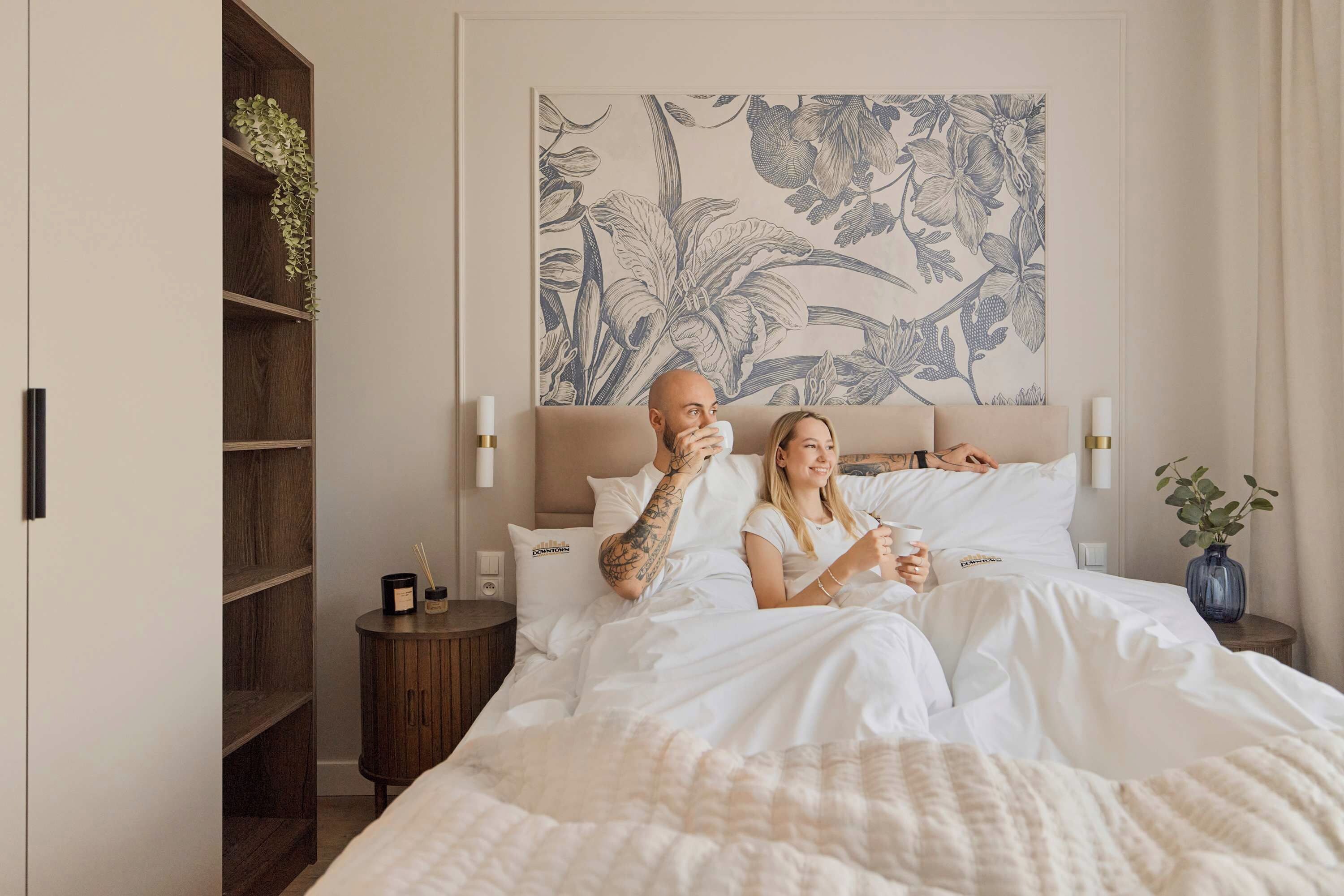 A bedroom with a bed, a nightstand, a wall-mounted artwork, and a wooden wardrobe.