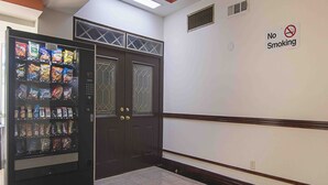 A vending machine with snacks, a no-smoking sign, and a double door entrance. - 2 Queen Beds | Premium, Micfridge (Decatur GA)