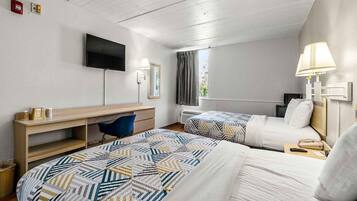 Habitación de hotel con dos camas, un escritorio, una silla, un televisor y una ventana con cortinas.