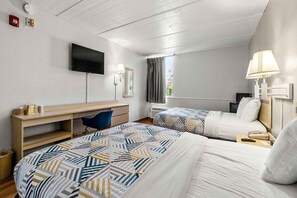 Habitación de hotel con dos camas, un escritorio, una silla, un televisor y una ventana con cortinas.