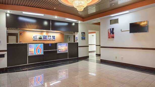 A hotel lobby with a reception desk, digital screens, a chandelier, and a tiled floor. - 2 Queen Beds | Premium, Micfridge (Decatur GA)