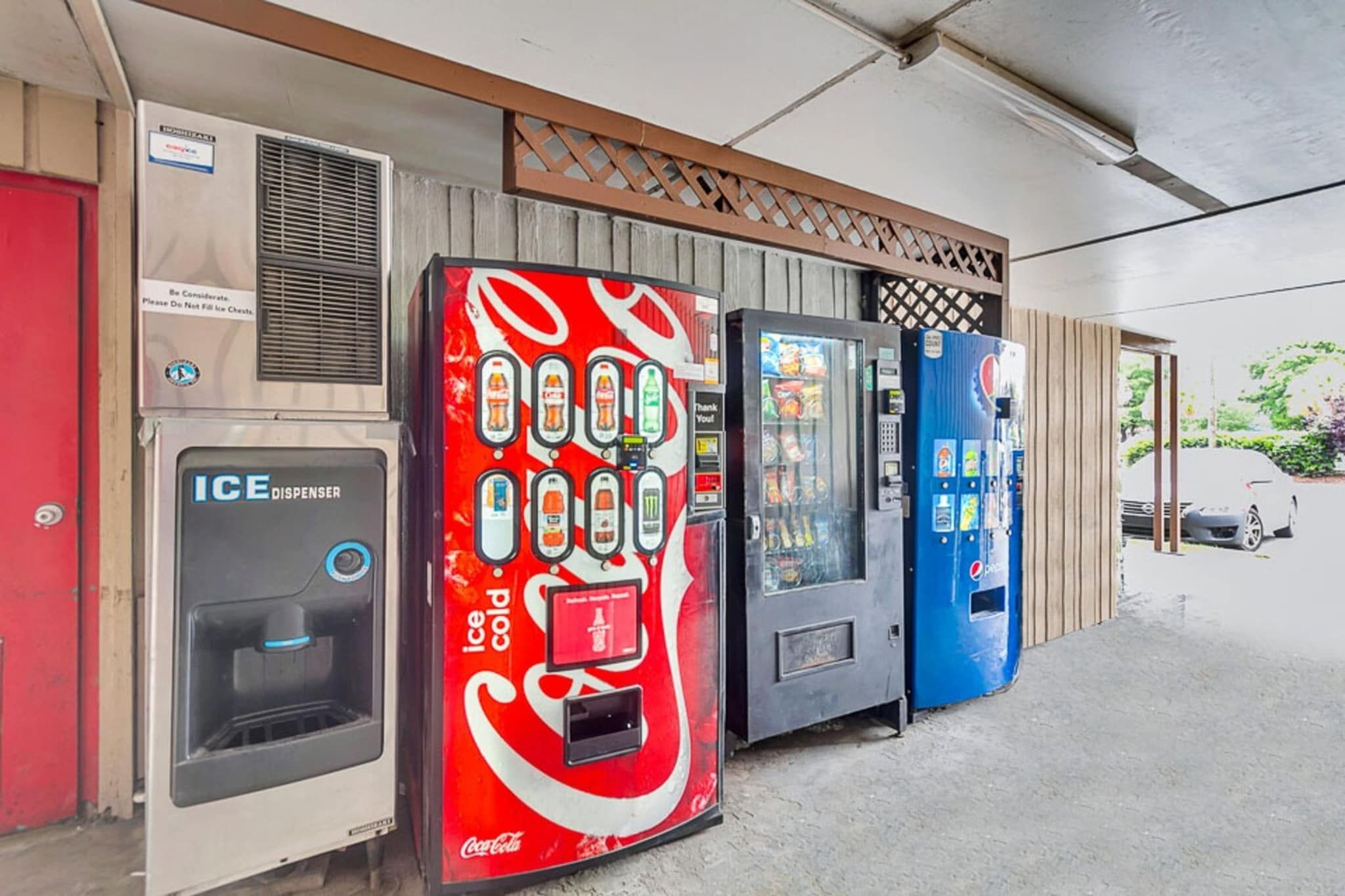 Eine Reihe von Verkaufsautomaten, darunter ein Eismaschine, ein Automat mit Coca-Cola-Branding und ein Pepsi-Automat.